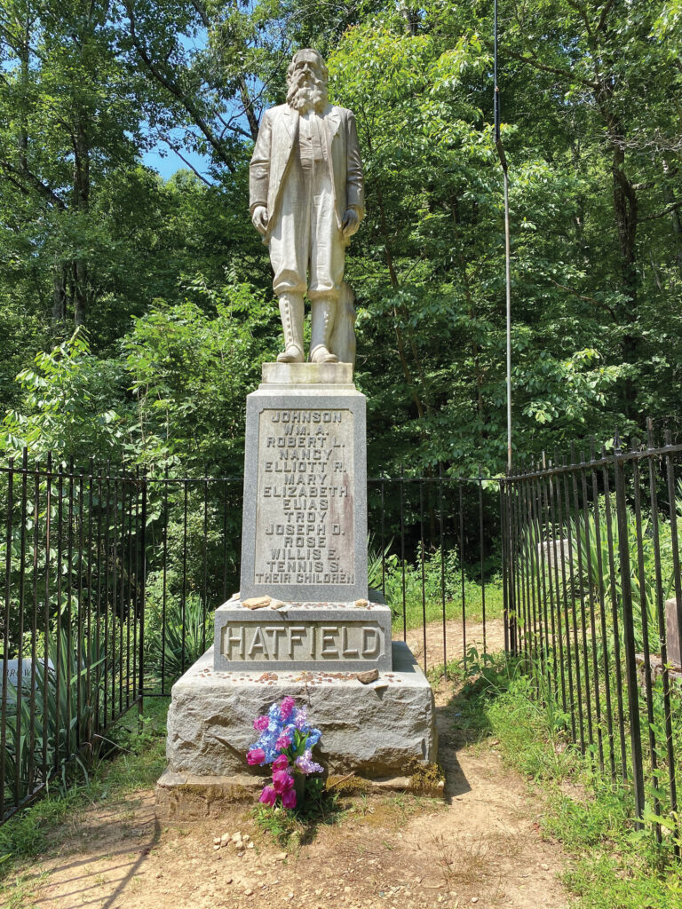 Statue of a grave marker that says Hatfield and has a sculpture of a man on top.