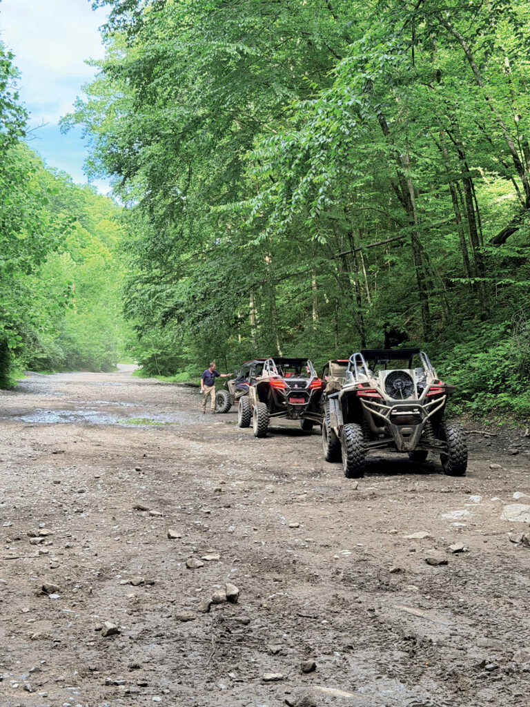 Side-by-side ATVS in a row on a dirt trail